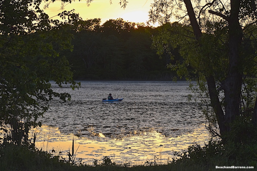 Fisherman kayaking in Atco Lake at sunset in Waterford Pine Barrens