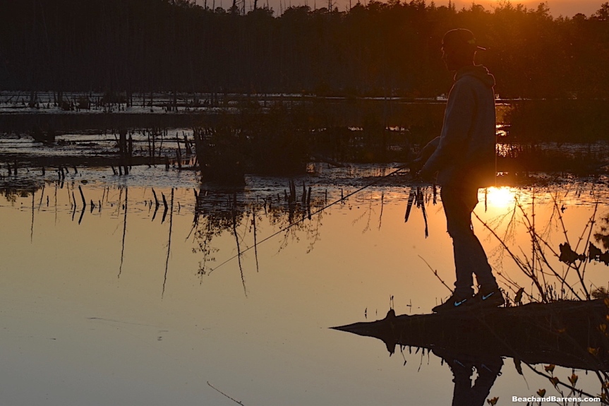 Fisherman silhouetted against sunset at Goshen Pond in the Pine Barrens